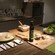 A table set with seasonings, utensils, a cutting board, garlic and a mortar and pestle